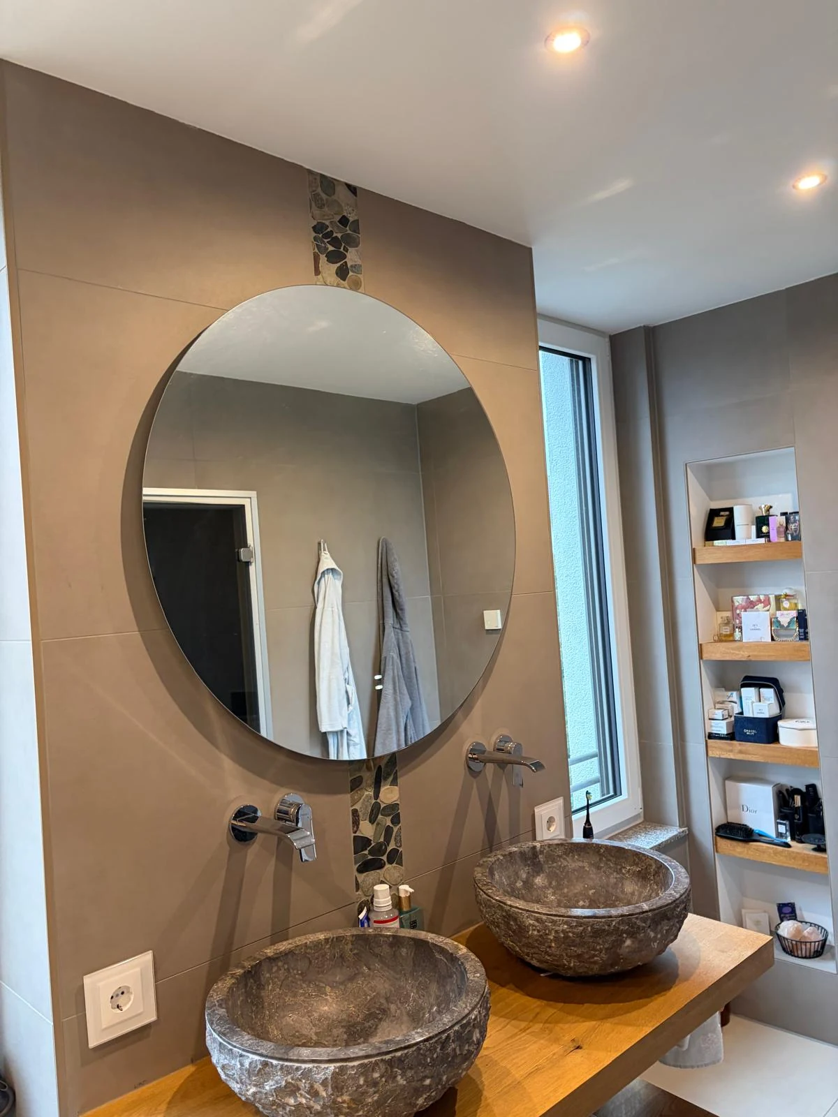 Badezimmer mit Doppelwaschbecken aus Stein und rundem Spiegel