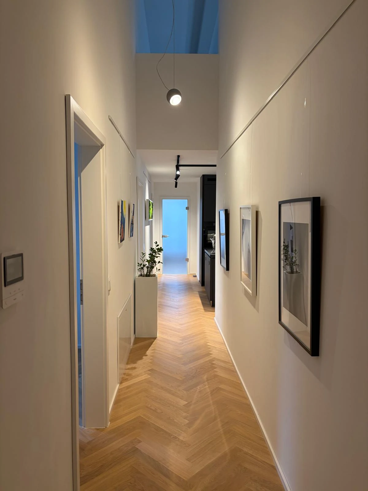 Langer, heller Flur mit hoher Decke und Fischgrätparkett