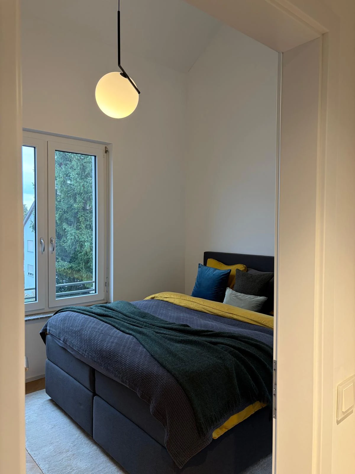 Ruhiges Schlafzimmer mit Fenster und zurückhaltender Gestaltung