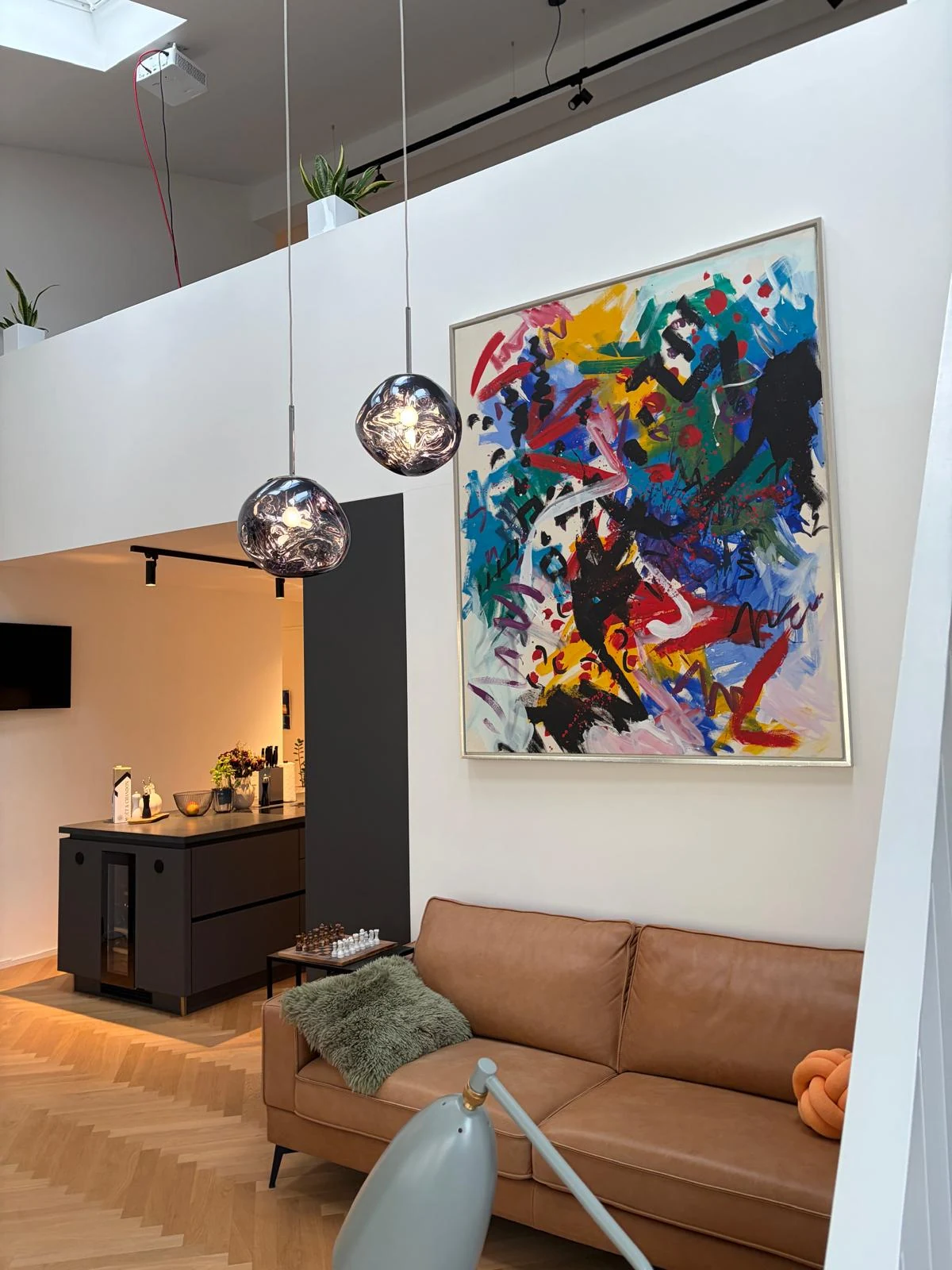 Blick auf den Wohnbereich mit Sofa, Kunstwand und Kücheninsel