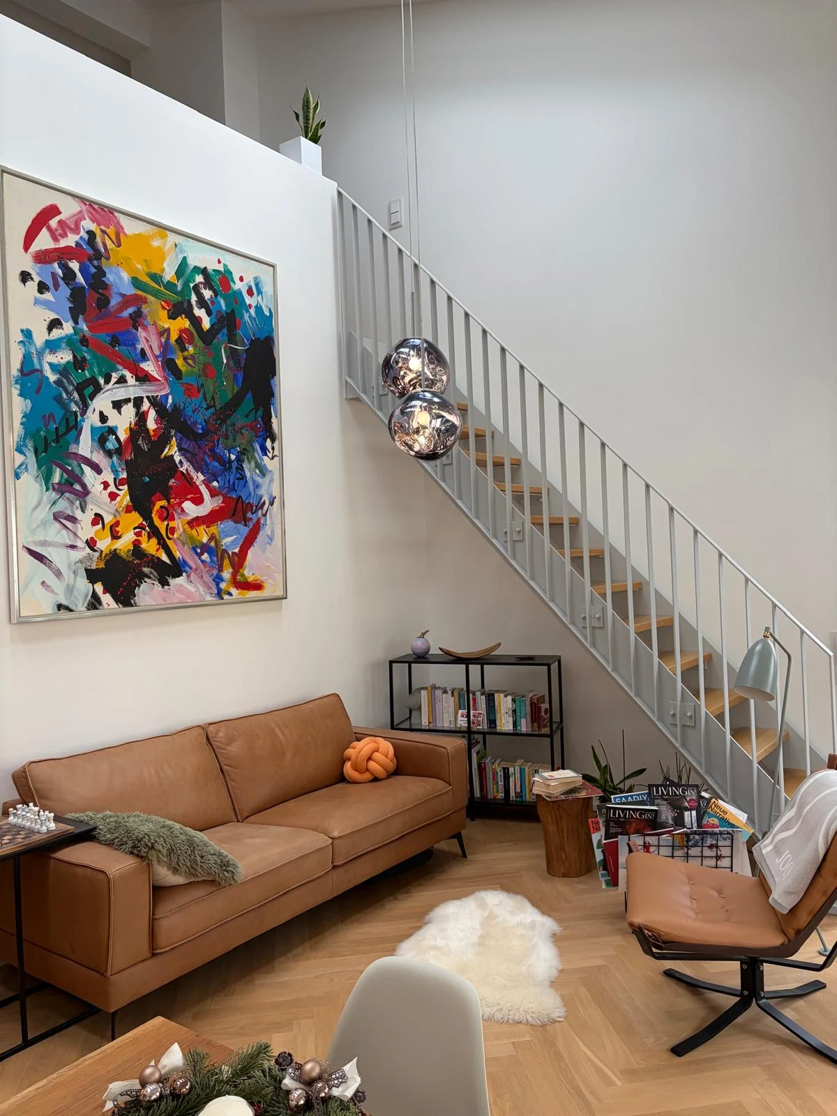 Wohnbereich mit Sofa, Kunstwerk und Treppe zur Galerie